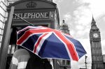 Tourist with British umbrella in telephone box and Big Ben in London